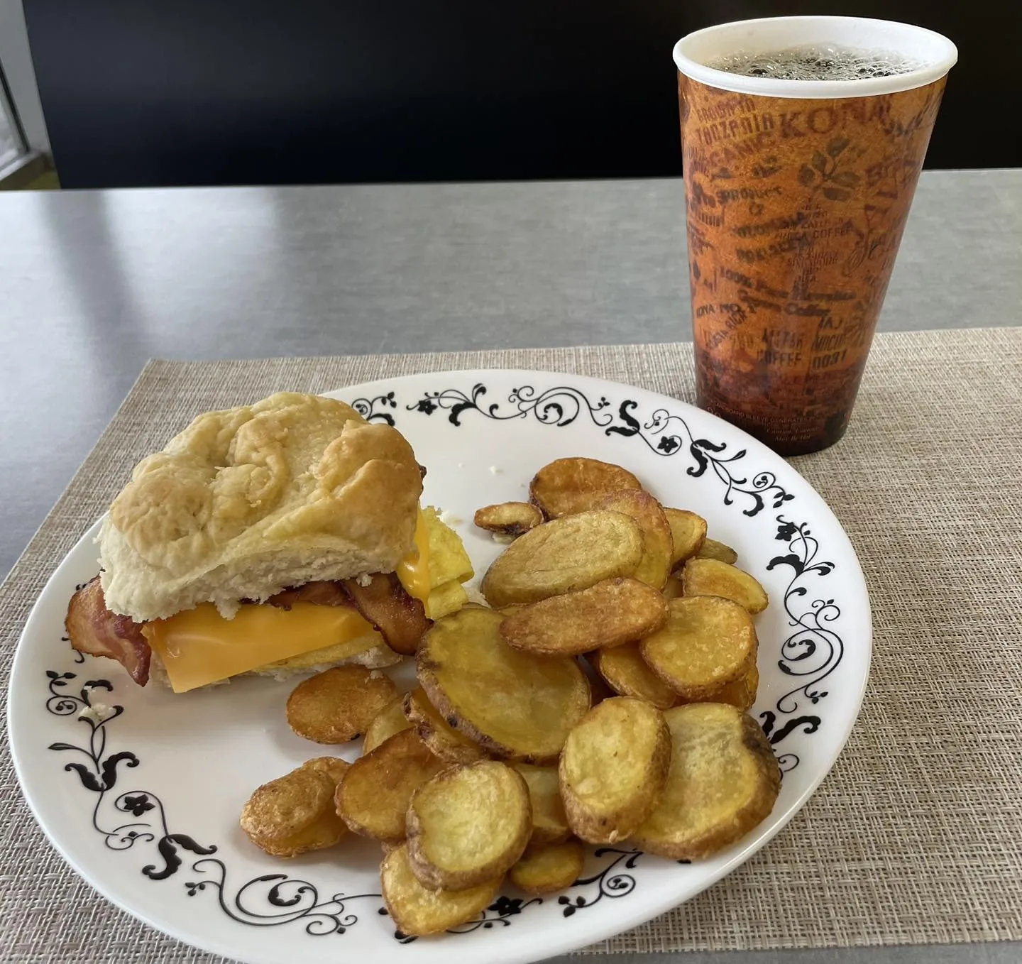 A Johnny's Combo: biscuit sandwich with fried potatoes and a large house coffee